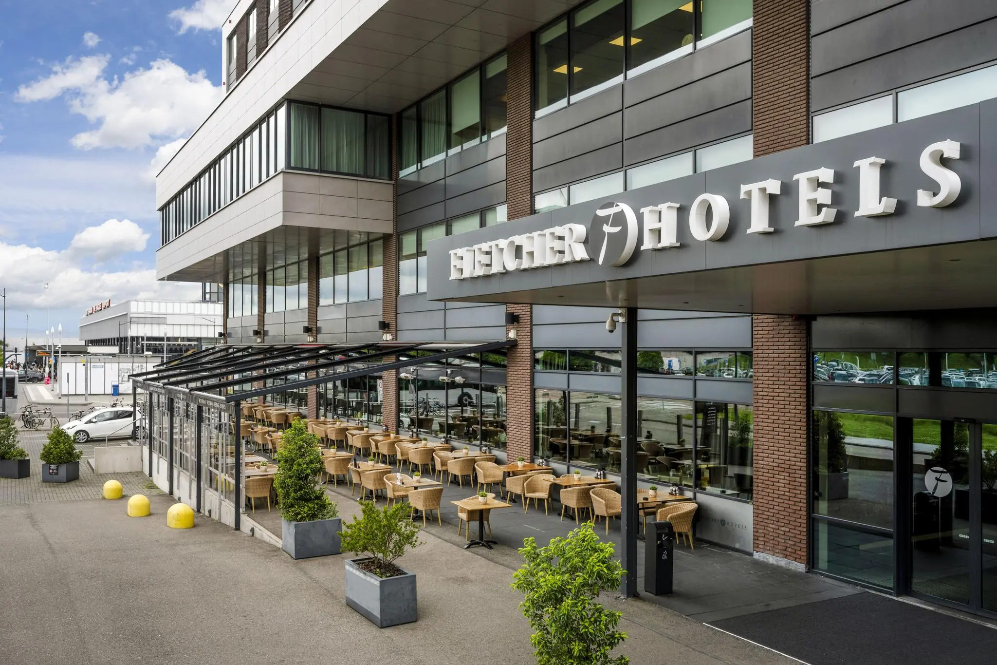 Buitenaanzicht van Fletcher Hotel aan het Airportplein bij Rotterdam The Hague Airport met een overdekt terras.